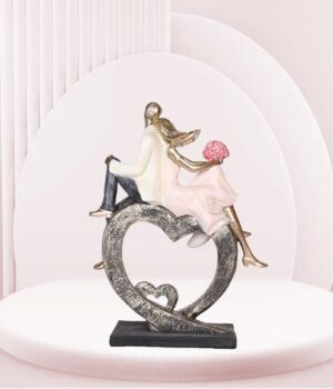 A romantic figurine of a couple sitting on a heart-shaped object.